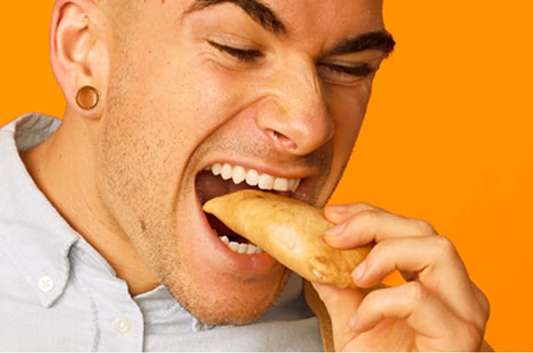 A guy eating a pizza pop